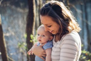 Postpartum depression woman carrying baby near trees
