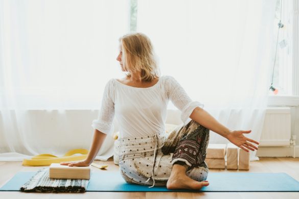 Yoga for menopause girl in white long sleeve shirt and blue pants sitting on white floor