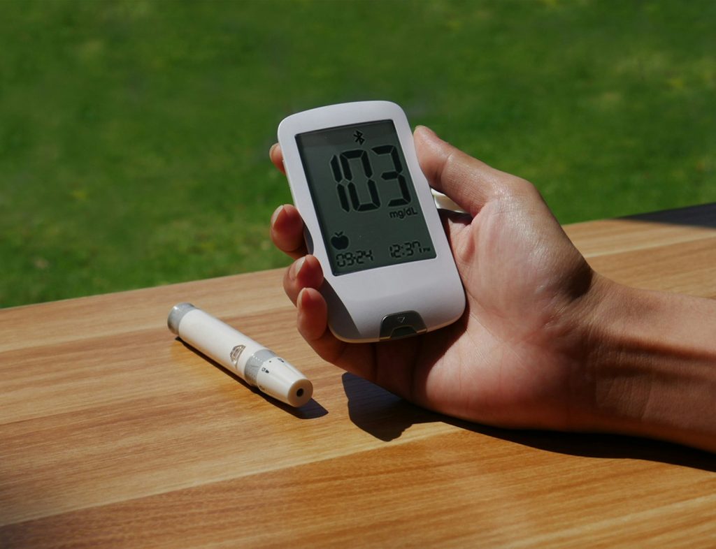 symptoms of type 2 diabetes a person holding a cell phone with a thermometer in their hand