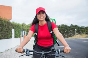 Live a healthy life Smiling woman courier riding bicycle for delivery service in Portugal.