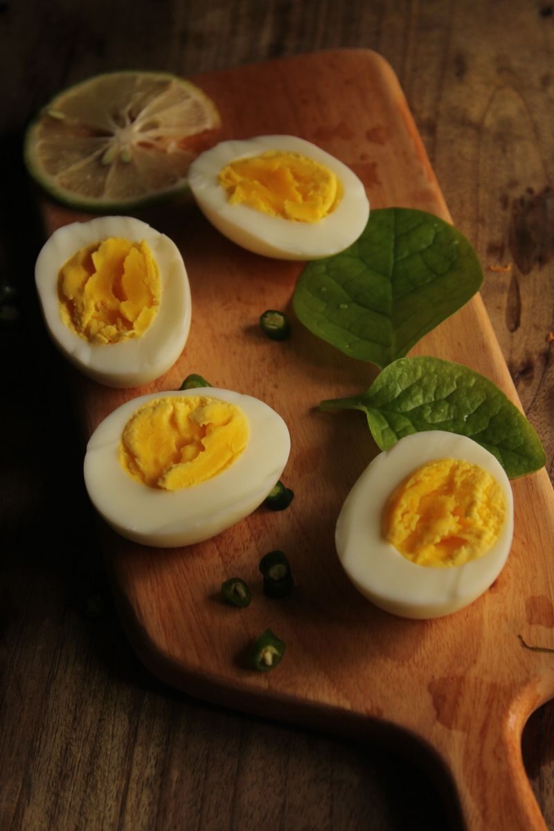 Protein sources Sliced hard-boiled eggs with spinach and lime on a wooden board