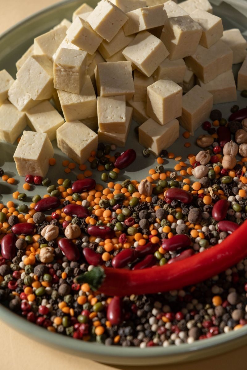 Protein sources Close-up of tofu cubes, chili pepper, and colorful beans on a plate.